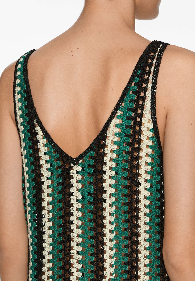 Top de ganchillo con diseño de escote en V, hecho de hilos verdes, negros y crema en un patrón alterno y con una textura de tejido abierto.