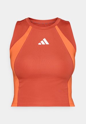Oranssi urheilu crop-top, joka on valmistettu sileästä ja joustavasta materiaalista. Siinä on urheilullinen racerback-muotoilu ja valkoinen logo edessä.