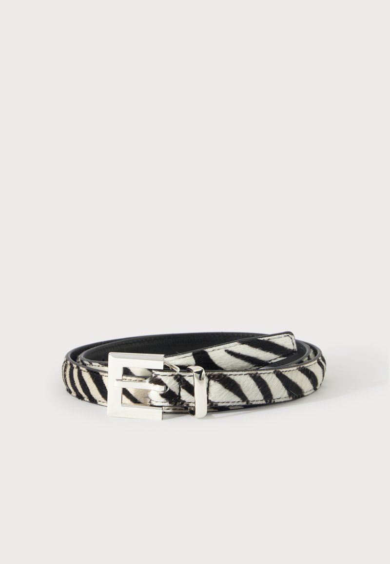 Ceinture zébrée noire et blanche avec une boucle rectangulaire argentée, enroulée sur un fond clair uni.