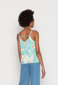 Uma blusa de alças em turquesa claro com um padrão floral, apresentando alças finas e um design de costas em forma de V. O material parece suave e macio.