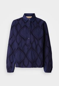 Blouse bleu marine à manches longues boutonnée avec col pointu et détails en motif losanges dentelle sur le tissu.