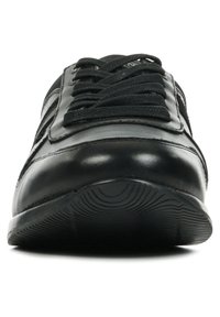 Scarpa atletica in pelle nera con lacci lavorati, suola in gomma piatta e accenti laterali. Presenta una punta arrotondata e una finitura liscia.