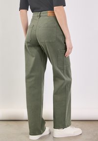 Groene cargobroek van katoen twill, met een hoge taille, zijzakken en een bruine leren patch op de achterkant. Soepele, rechte pijpen.