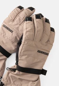 Guanti invernali beige con accenti neri, caratterizzati da un design trapuntato, cinturini regolabili ai polsi e il logo "Burton" ricamato sulla parte posteriore.