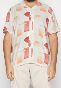 Camicia a maniche corte con bottoni in tessuto leggero, caratterizzata da motivi astratti in tonalità di rosso e arancione su uno sfondo crema.