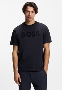 Czarny bawełniany t-shirt z wypukłym logo "BOSS" na środku, krótkimi rękawami i okrągłym dekoltem, o gładkiej fakturze.