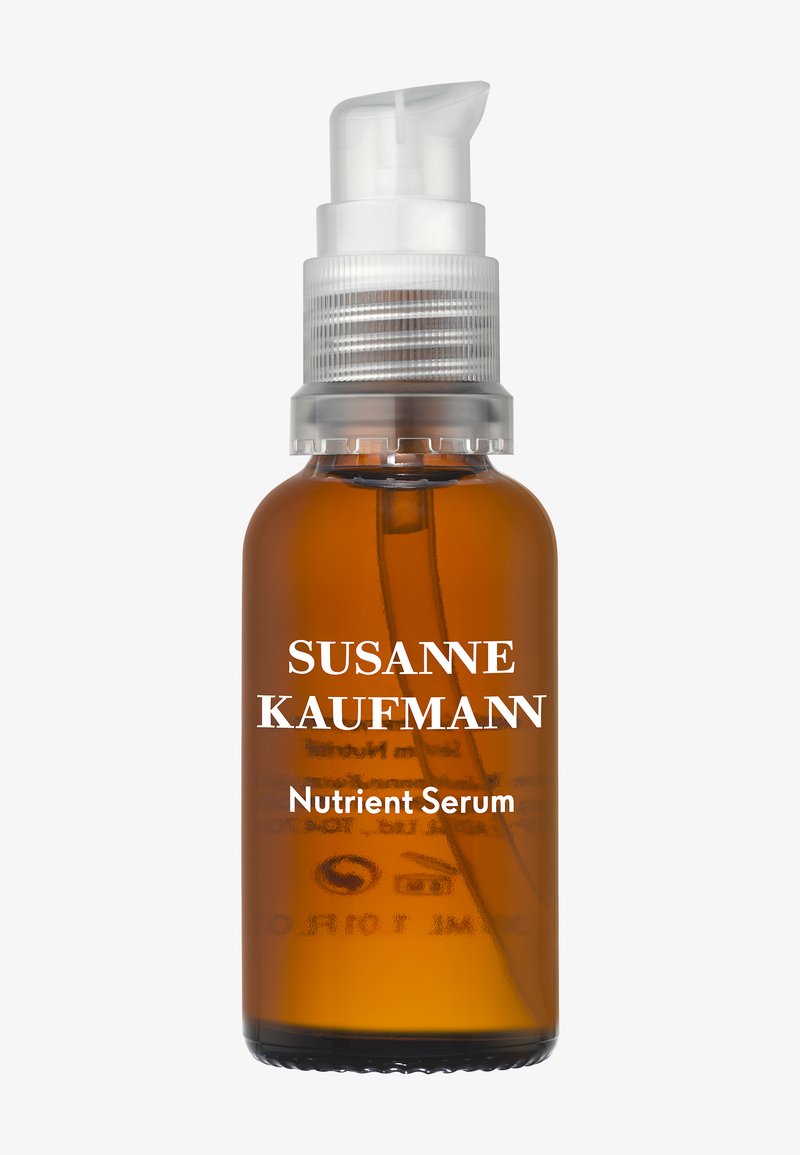 Bernsteinfarbene Pumpspender-Flasche mit der Aufschrift "Susanne Kaufmann Nutrient Serum" und klarem Kunststoffpumpenspender, der die Flüssigkeit im Inneren zeigt.