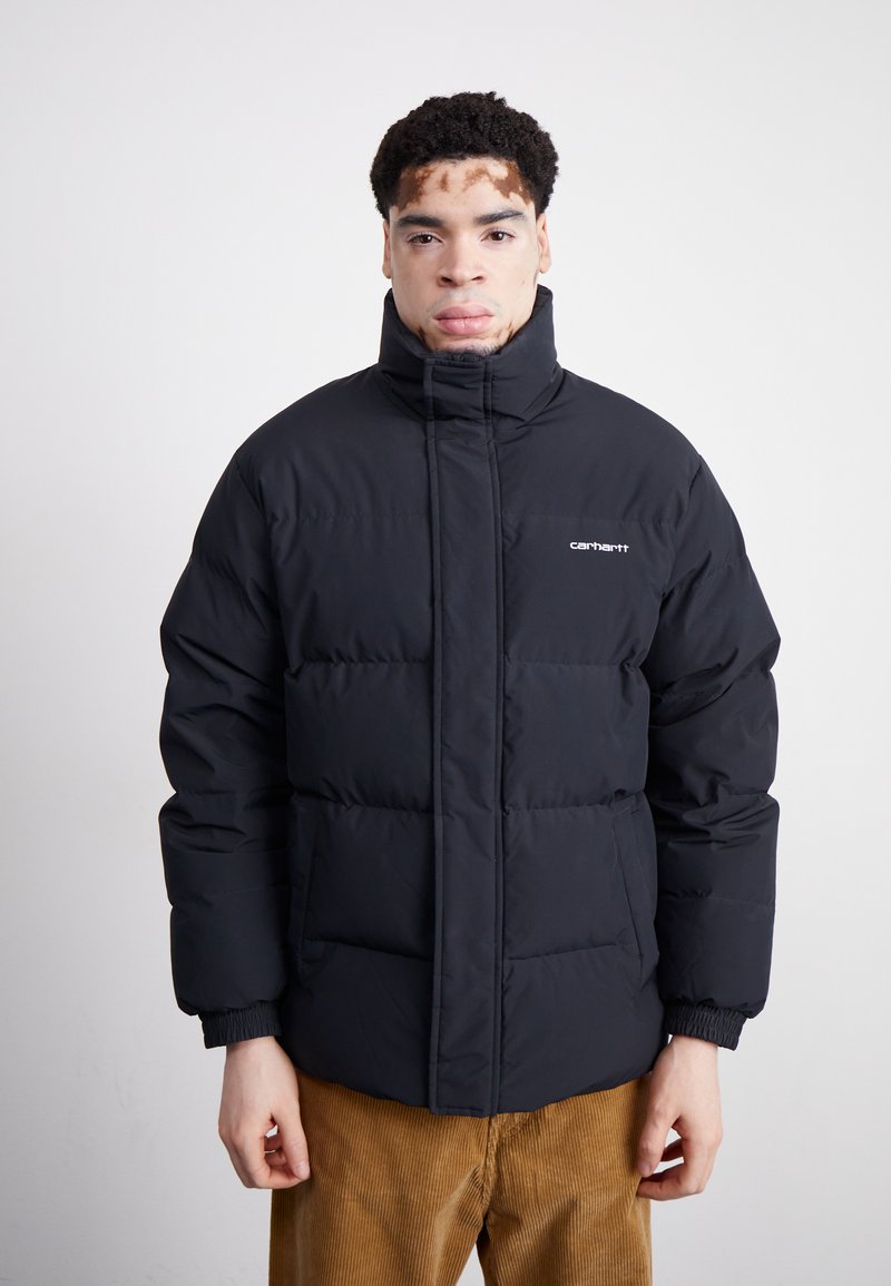 Schwarze Daunenjacke mit hohem Kragen, gestepptem Design und elastischen Bündchen. Verfügt über Fronttaschen und ein kleines Logo auf der Brust.