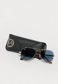 Occhiali da sole Ray-Ban aviator con lenti blu scuro e montatura in metallo dorato, accompagnati da una custodia in pelle nera texture con logo.