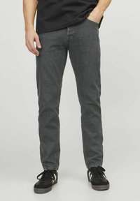 Mørkegrå denimjeans med slim fit. Forlommer og en tonet syning. Sættet er parret med sorte sneakers med hvide detaljer.