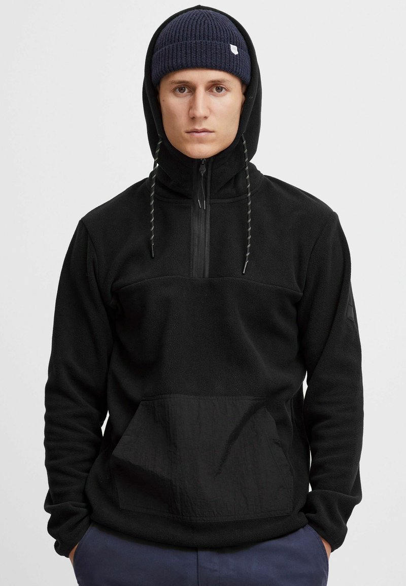 Schwarzer Fleece-Pullover mit Halbreißverschluss, Kapuze und frontaler Tasche. Verfügt über einen strukturierten Stoffbereich, verstellbare Kordeln und eine ribbelgestrickte Mütze.