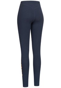 Leggings blu navy con vita alta, realizzati in tessuto elasticizzato, con un design di testo verticale arancione sulla gamba sinistra.