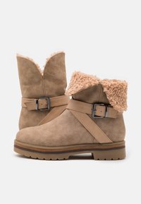 Ruskean mokkanahka nilkkurit, joissa on pörröinen beige varsi, säädettävä hihna ja metallivaimennuskoristeet, kumipohja, jossa on kuvioitu pito. Rentoa muotoilua.