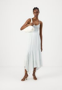 Gaiši zils, plūstošs maksi kleita ar regulējamiem siksniņām, mežģīņu apdare pie krūšu daļas, plīvurotām malu malām, apvienota ar baltu rokassomu un brūnām čībām.