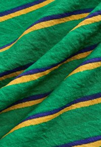 Tissu vert avec des plis texturés, présentant des rayures diagonales jaunes et bleues traversant la surface.