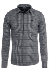 Camicia a maniche lunghe bianco e nero a fantasia con colletto button-down, dotata di taschino sul petto e tessuto texture.