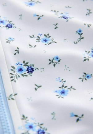 Motif de tissu floral présentant de petites fleurs bleues et violettes sur fond blanc, avec des feuilles vertes ; texture douce et conception légère.