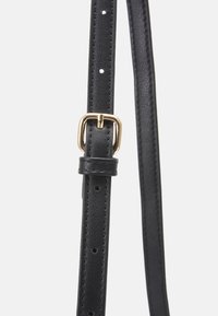 Cinghia in pelle nera con fori regolabili, dotata di una fibbia in metallo dorato. Texture liscia con cuciture precise lungo i bordi.