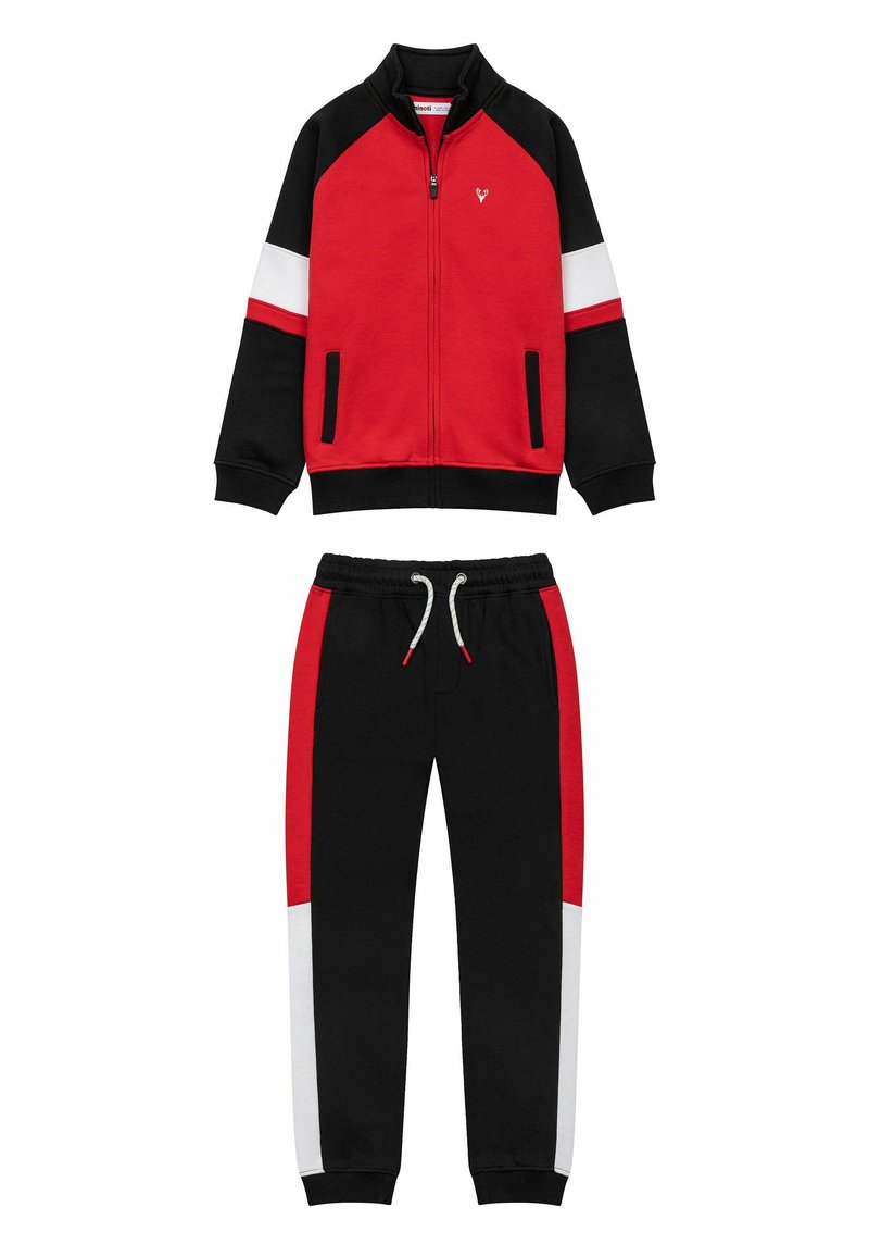 Rode en zwarte trainingsoutfit met witte en rode accenten, een ritsjack en elastische taillebandbroek met zijzakken. Zachte stoftextuur.