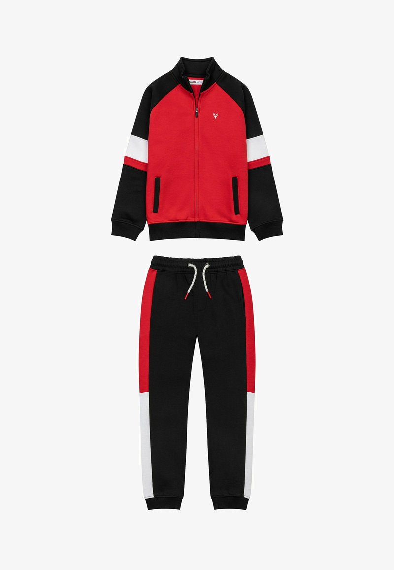 Röd och svart träningsdräkt med vita och röda accenter, zip-up jacka och byxor med elastisk midja och sidfickor. Mjuk tygtextur.