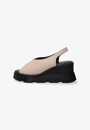 Beige leather slingback shoes with a rounded toe and ridged black platform sole, featuring a cut-out design and a textured insole.