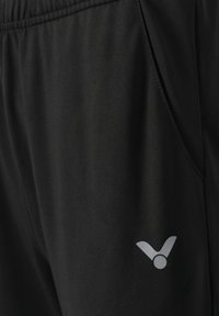 Sorte træningsbukser lavet af letvægtsstof, med elastisk talje og et lille hvidt logo på nederste venstre side.