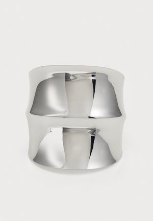 Bague en argent à surface lisse et réfléchissante. Présente un design courbé et une large bande, créant un look moderne et minimaliste.