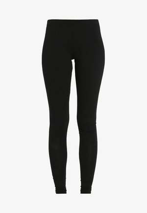 Juodos leggingai, pagaminti iš elastingos medžiagos, su prigludusia forma ir nesiūlėmis juosmeniu, su subtilu susirinkimu ties kulkšnimis.