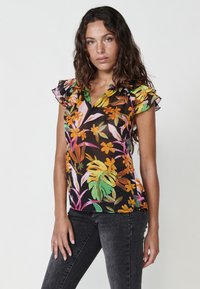 Blusa floreale con vivaci motivi arancioni, rosa e verdi su uno sfondo nero. Maniche arricciate e design a scollo a V.