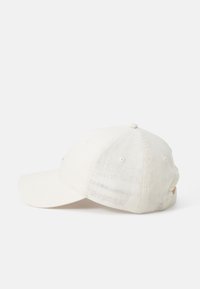 Gorra de béisbol blanca de algodón ajustable con visera curva, agujeros de ventilación cosidos y un detalle de botón en la corona.