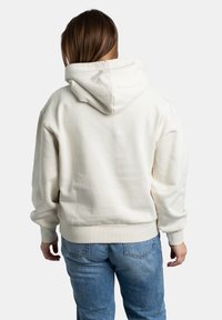 Crème hoodie met een ruime capuchon en geribbelde manchetten, gemaakt van zachte stof. De achterkant heeft een relaxte pasvorm en subtiele naden. Gecombineerd met lichte denim.
