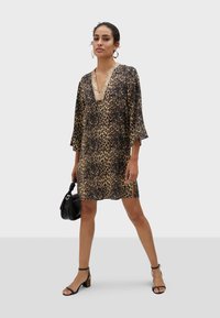 Haljina s leopard uzorkom, V-izrezom i ukrašenim izrezom. Izrađena od laganog materijala, sa zvonastim rukavima i bočnim prorezom. Uključena crna torbica.