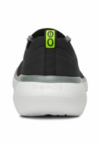 Black slip-on shoe with a textured upper, a white midsole, and a green accent at the heel, featuring a smooth finish and minimalistic design.