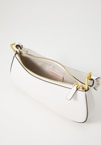Borsa a tracolla in pelle bianca con forma strutturata, hardware dorato, chiusura con cerniera e interno beige con etichetta del marchio.