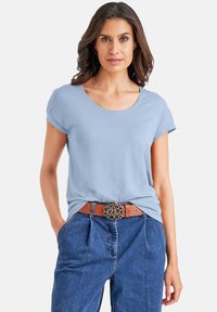  Lichtblauw T-shirt met korte mouwen en een ronde hals, gecombineerd met high-waisted jeans van denim en een bruine riem met een decoratieve gesp.
