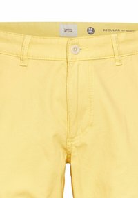 Gule bomuldsbukser med en regular fit. Har en knaplukning, sidelommer og kontrasterende stikning. Etiketten er synlig ved taljen.