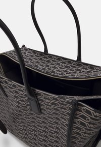 Black and gray tote bag with double handles, zippered top, and repeating stylized logo pattern on fabric exterior.