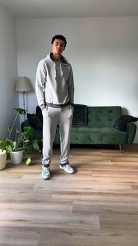 Gray, fleece hoodie and matching joggers with a black waistband. White sneakers. Simple design with no visible logos or patterns.