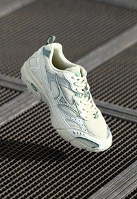 Zapatillas con parte superior de malla blanca cremosa y acentos en verde menta, suela texturizada y elementos de diseño minimalistas. Incluye cordones.