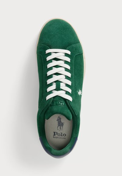 Adidași din suede verde cu șireturi albe, având un logo și numele brandului pe limbă, și un accent contrastant de culoare albastru închis la călcâi.