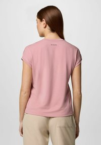 T-shirt rosa chiaro a maniche corte con scollo rotondo e trama sottile. Presenta un piccolo logo Columbia sulla parte superiore della schiena.