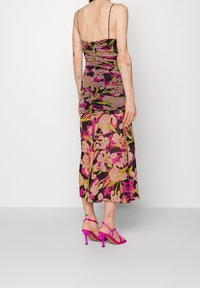 Floral print dress with a fitted bodice and flared skirt, featuring pink and green hues, made from soft fabric. Paired with bright pink heels.