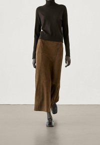 Brown turtleneck sweater paired with tan suede wide-leg trousers. Displays a smooth texture, relaxed fit, and black flat shoes.