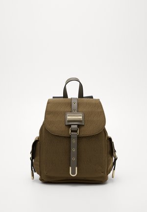 Mochila marrón con un patrón de logotipos texturizados, solapa superior, correas de hombro ajustables y detalles en tono dorado. Cuenta con un cierre de correa frontal.