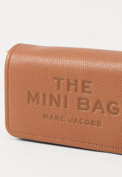 Geantă mini din piele texturată de culoare maro deschis, cu text debossat "THE MINI BAG" și "MARC JACOBS." Prezintă colțuri rotunjite și cusături vizibile.