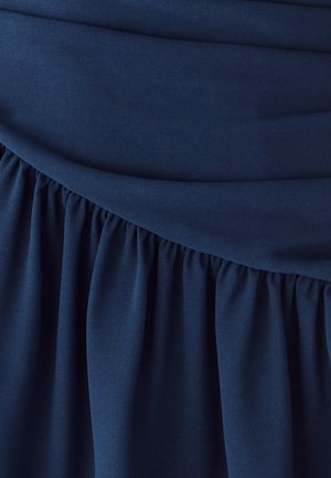 Tela azul marino con textura suave que presenta un detalle fruncido en el dobladillo y un diseño sólido plisado en el cuerpo de la prenda.