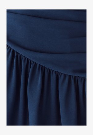 Tela azul marino con textura suave que presenta un detalle fruncido en el dobladillo y un diseño sólido plisado en el cuerpo de la prenda.