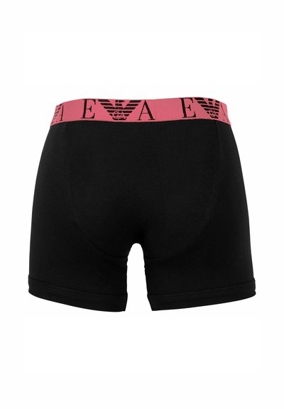 Schwarze Unterwäsche mit einem pinken elastischen Bund, der ein schwarzes Logo und ein Adlerdesign zeigt. Der Stoff ist glatt und eng anliegend, mit einer mittellangen Beinlänge.