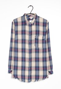 Chemise à carreaux à manches longues en tissu doux bleu, beige et bordeaux, avec une poche et un ourlet effiloché en bas.