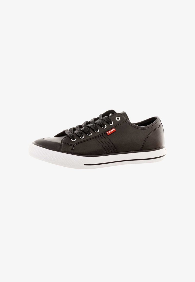 Baskets en cuir noir avec un bout rond, dotées de lacets gris, d'une semelle en caoutchouc blanche et d'une étiquette logo rouge. Texture lisse avec des accents de design minimalistes.
